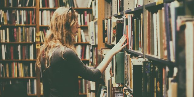 kobieta przeglądająca książki w bibliotece